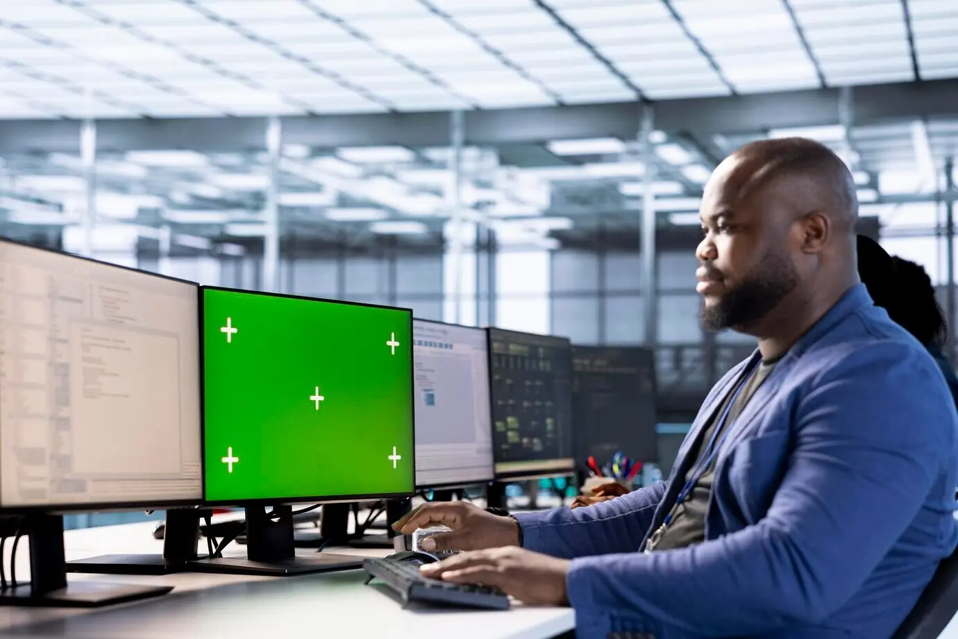 Сотрудник в серверном хабе использует компьютер с зелёным экраном для поиска ошибок конфигурации.